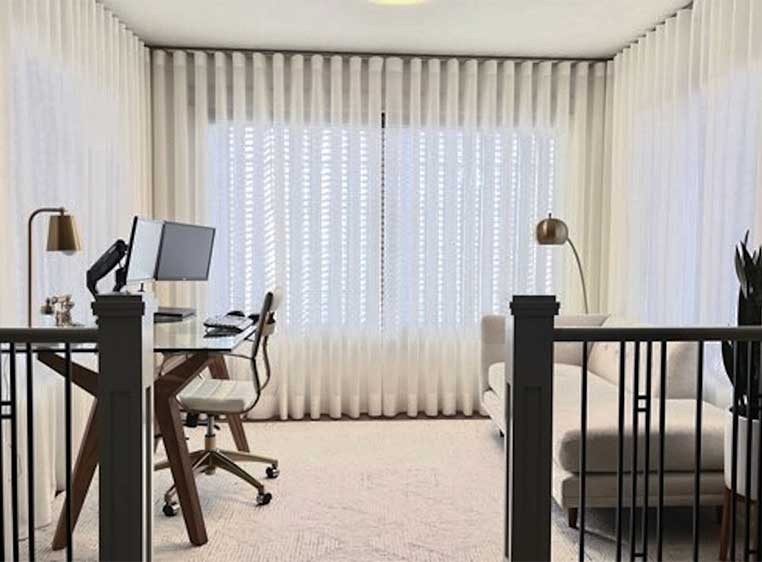 Small office area with soft light coming trough sheer drapes
